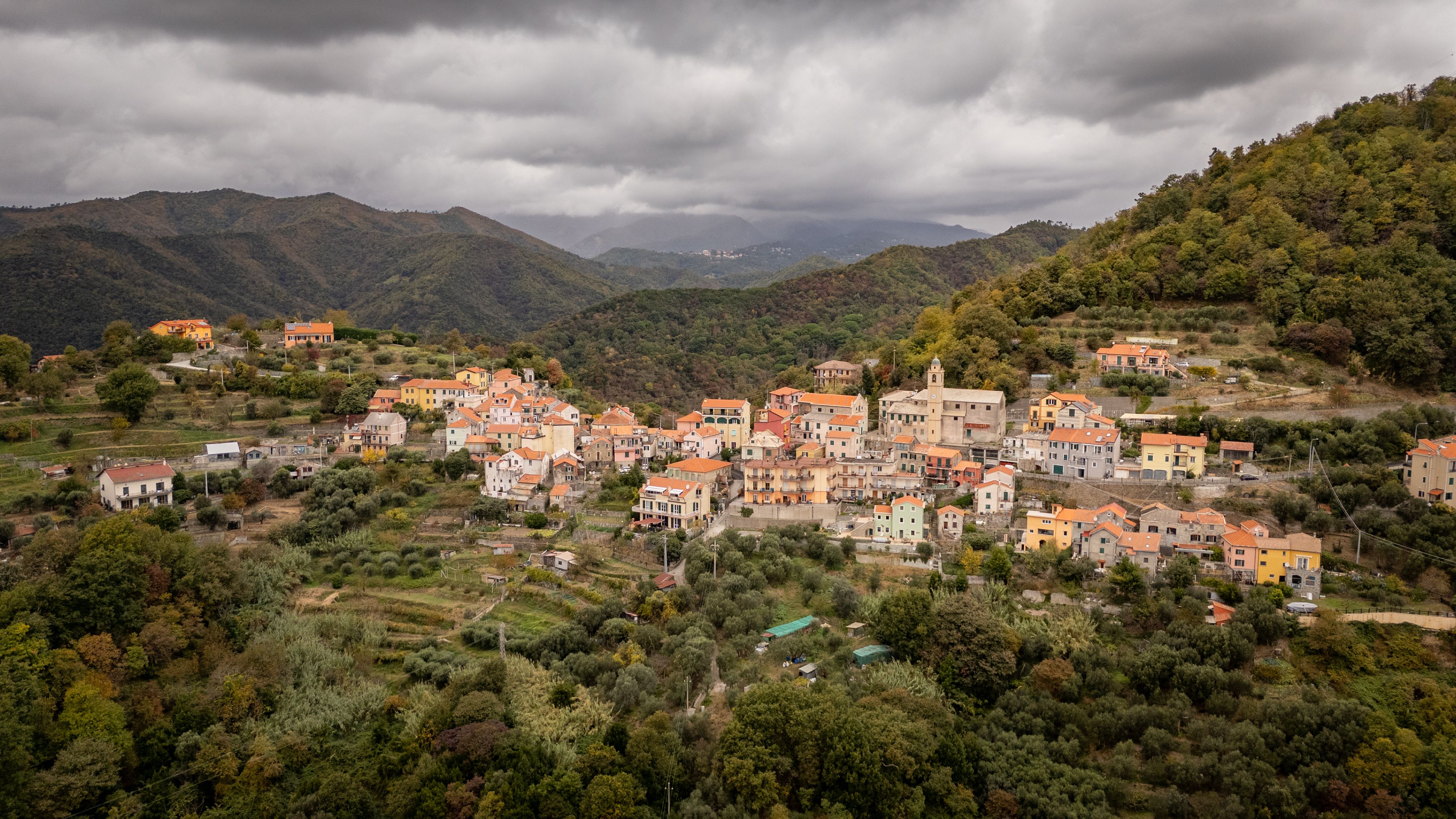 Picturesque aerial view of Gameragna, Liguria, Italy with colorful houses and lush green hills.