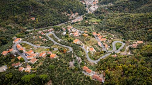 Free Aerial view of winding roads and houses in Gameragna, Liguria, Italy, amidst lush greenery. Stock Photo