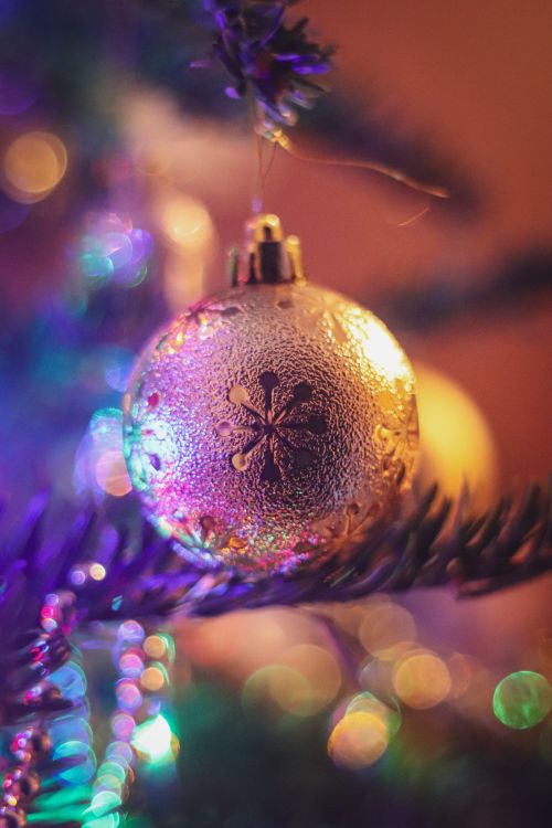 Free Close-up of a shimmering Christmas ornament with bokeh lights behind, capturing holiday spirit. Stock Photo