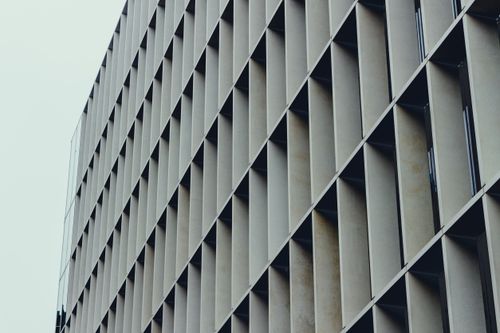 Free Low-angle view of a modern geometric skyscraper facade showcasing urban architecture and design. Stock Photo