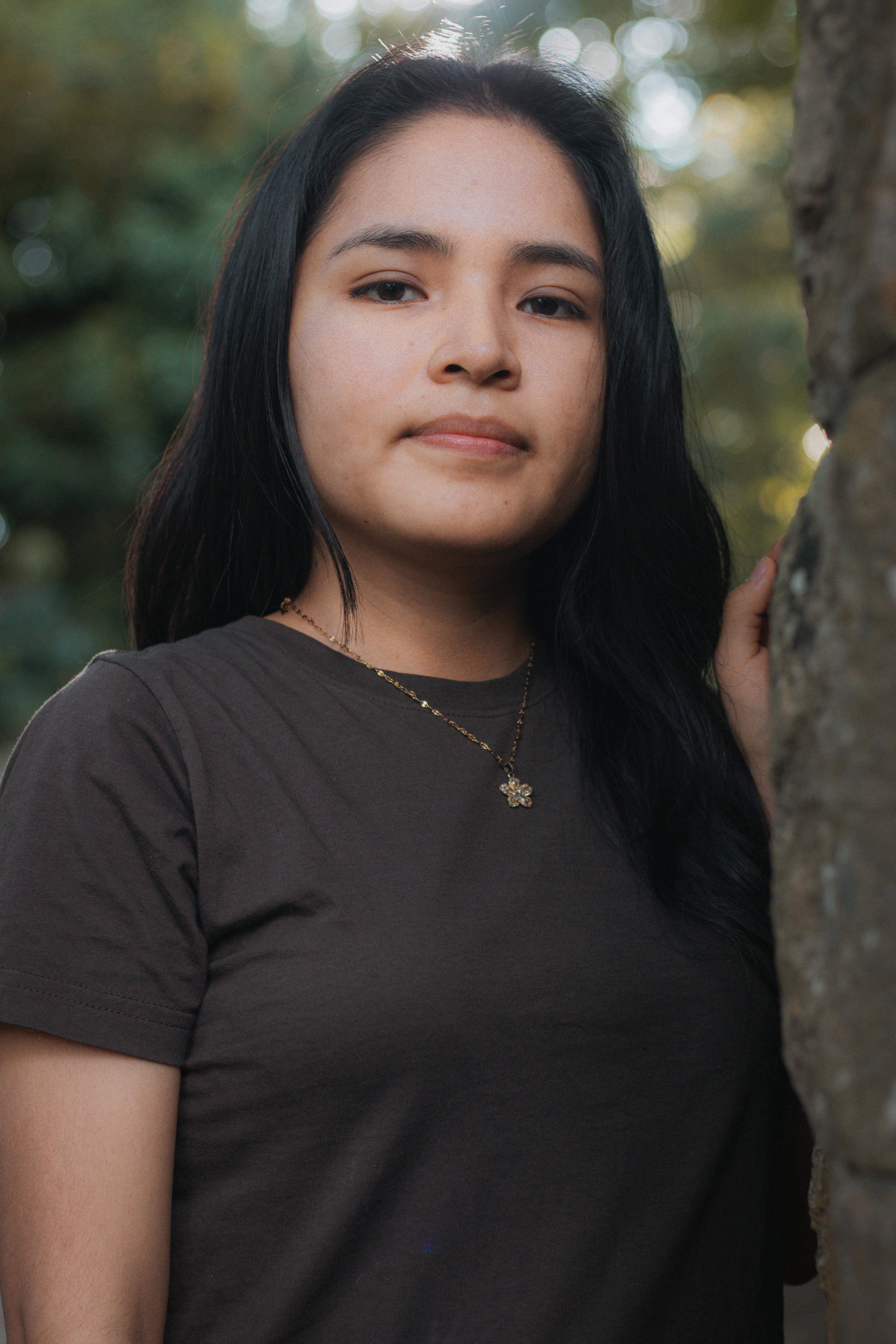 A serene portrait of a young woman standing outdoors, embracing nature.
