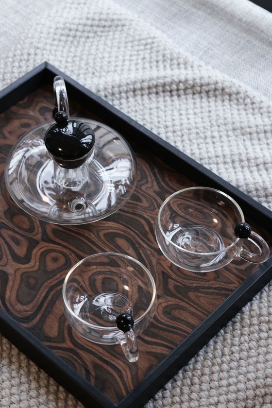 Glass teapot and cups set on a lacquered serving tray — photo by JunHao Yuan on Pexels