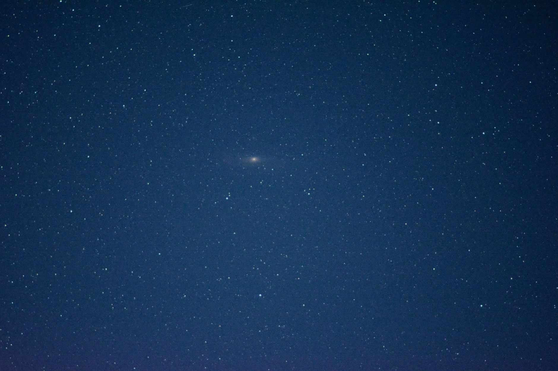 A clear night sky showcasing the distant Andromeda Galaxy among scattered stars.