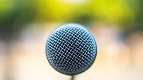 A microphone on a stand outdoors, ready for a public speaking or musical performance.
