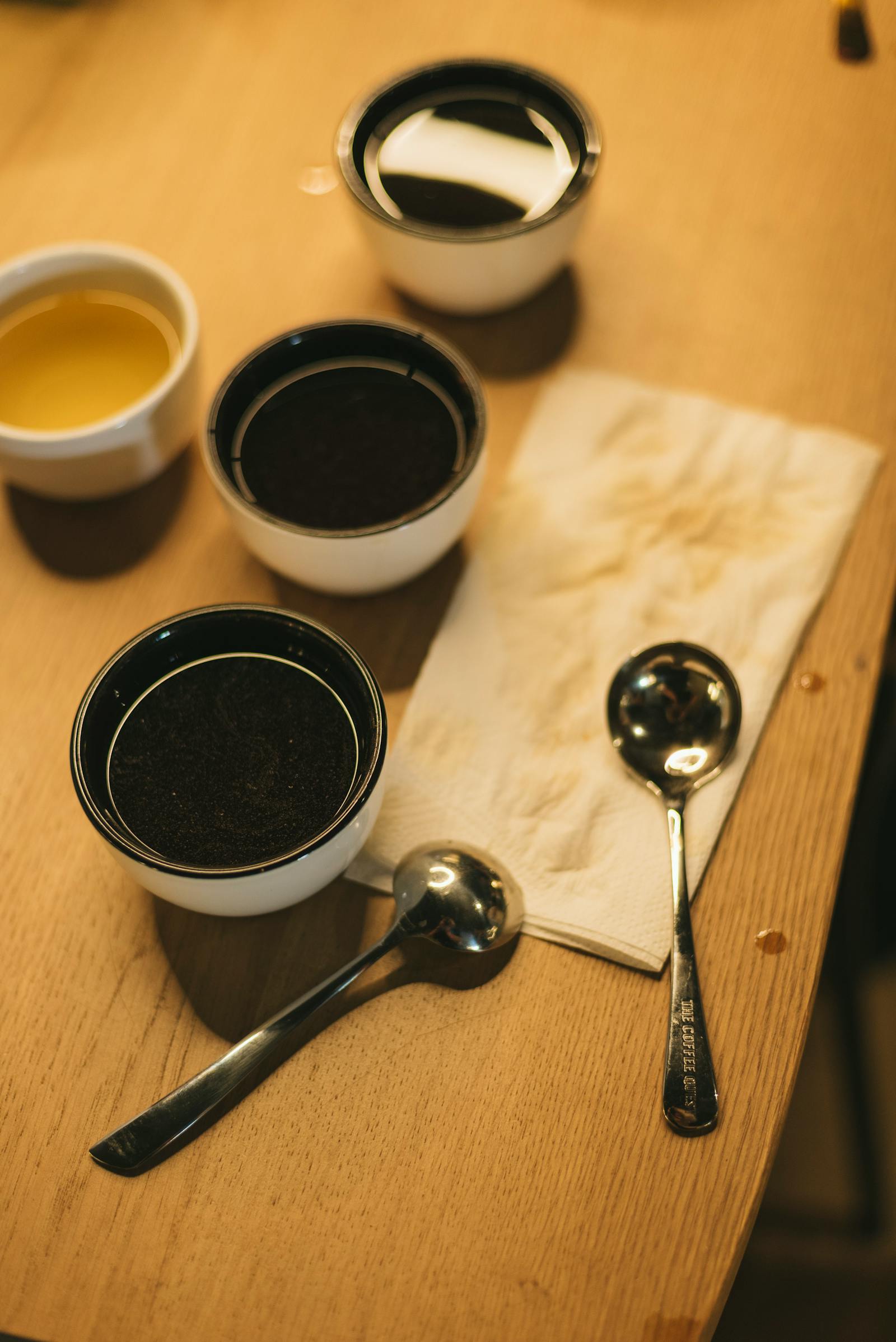 Cup of coffee on table with cupping bowls and spoons