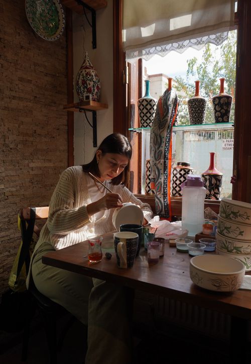 Free A woman skillfully paints ceramics in a sunlit studio in Bursa, Türkiye. Stock Photo