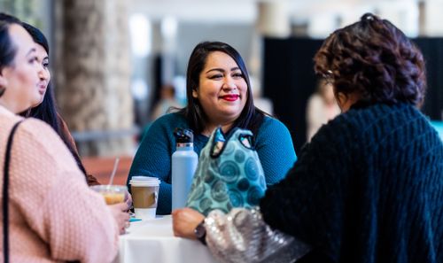 Free Group of women enjoying coffee and conversation at a table indoors. Stock Photo