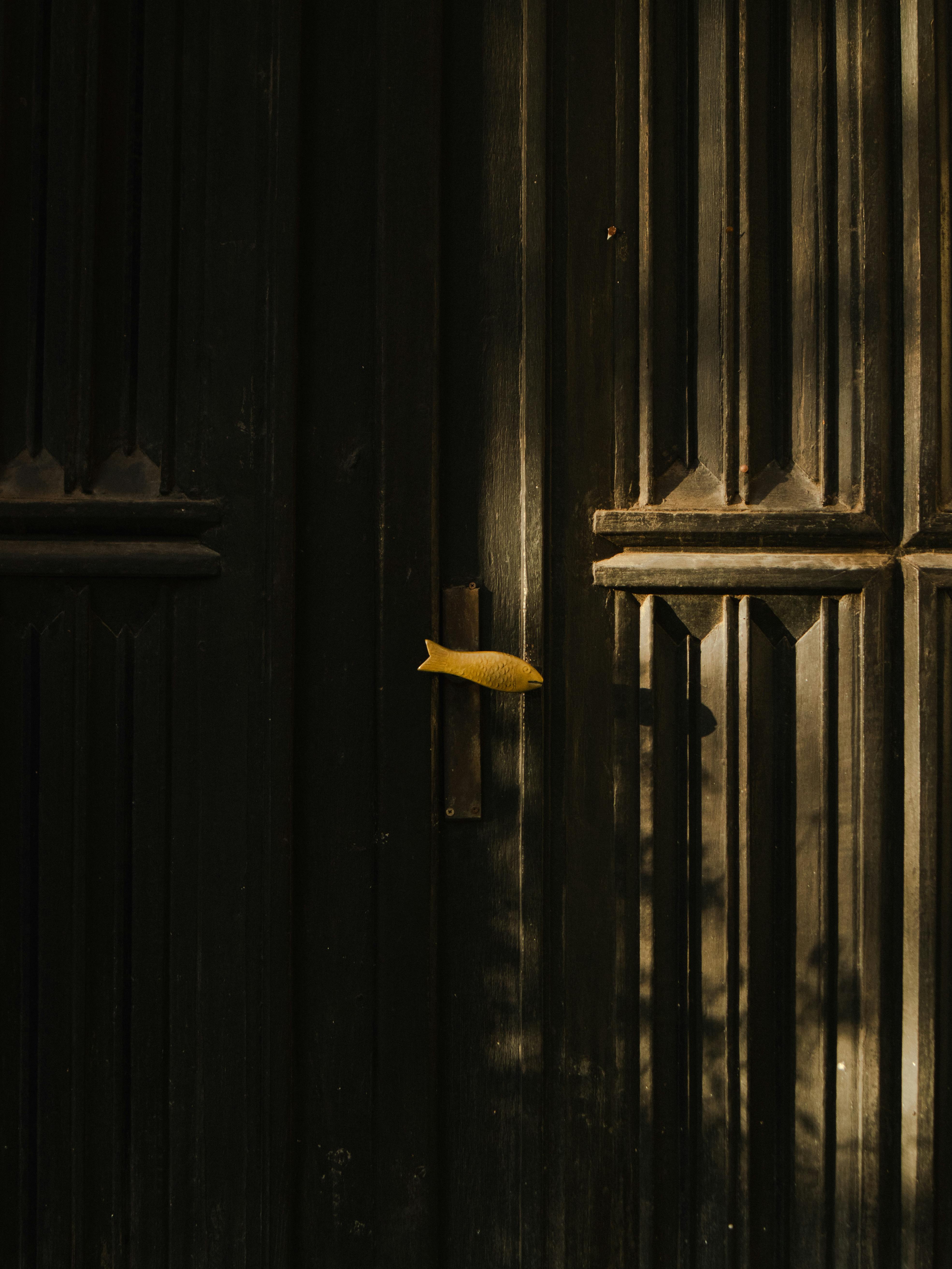 Dark minimalist door design featuring a contrast yellow handle, perfect for editorial use.