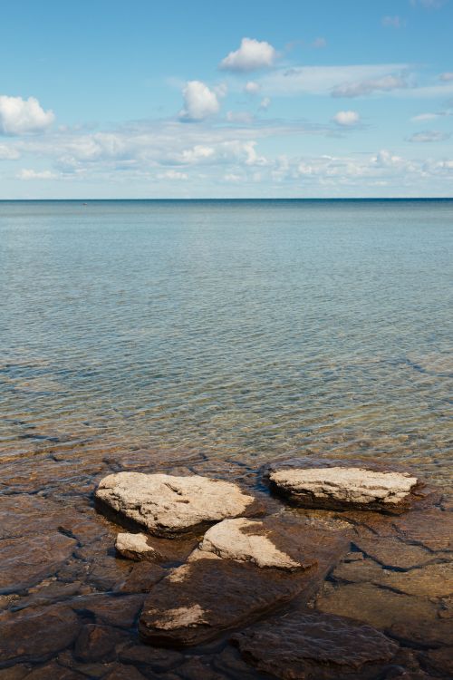 Free Serene view of Lake Michigan with clear blue sky and rocky shoreline in Wisconsin. Stock Photo