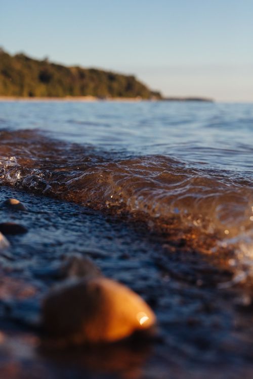 Free Low angle view of gentle waves on the rocky shoreline of Lake Michigan at sunset in summer. Stock Photo