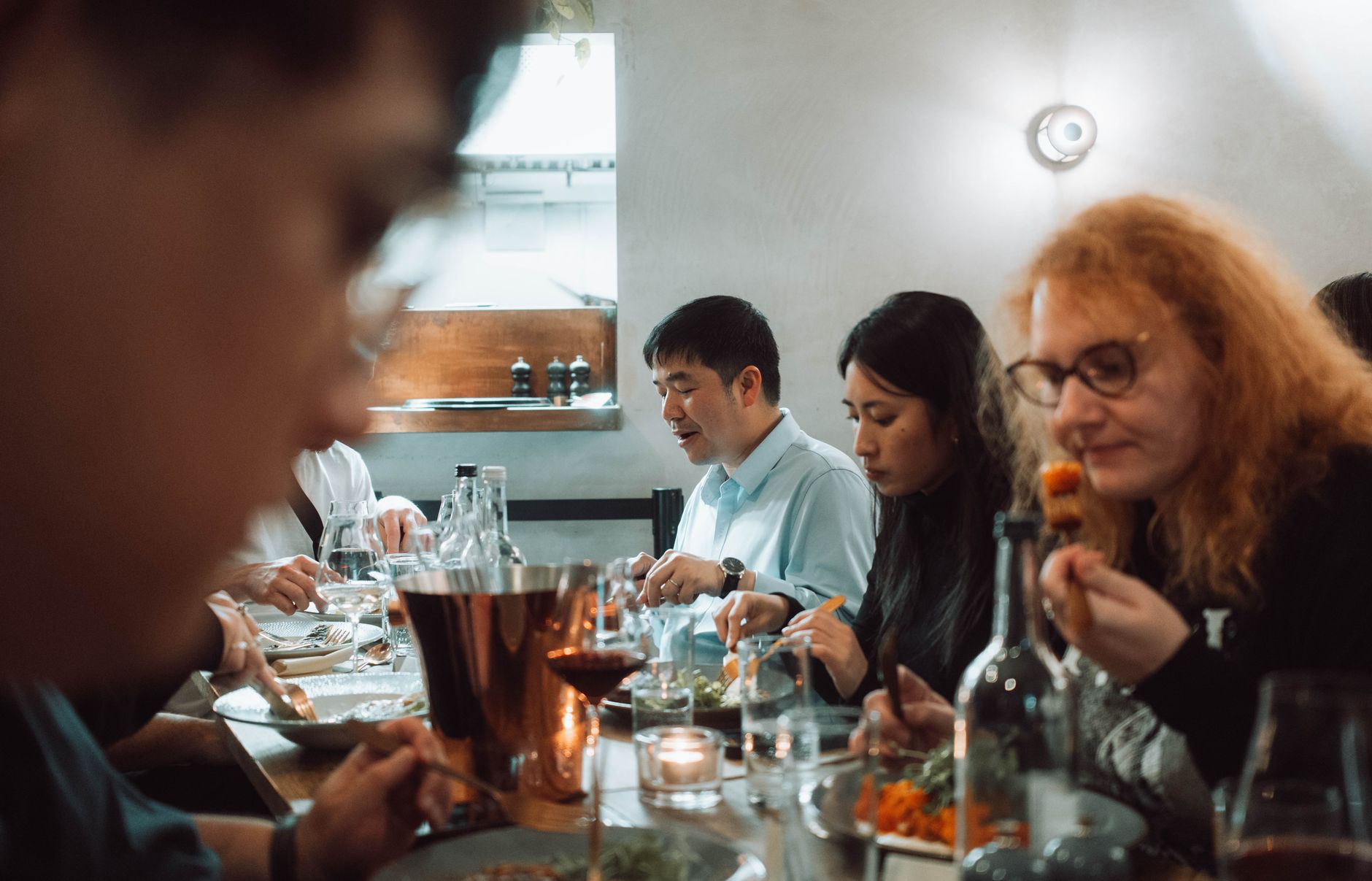 A diverse group of adults enjoying a meal together in a cozy indoor restaurant setting.