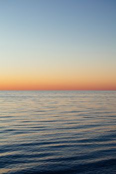 Tranquil view of Lake Michigan at sunset with a clear sky and gentle waves.