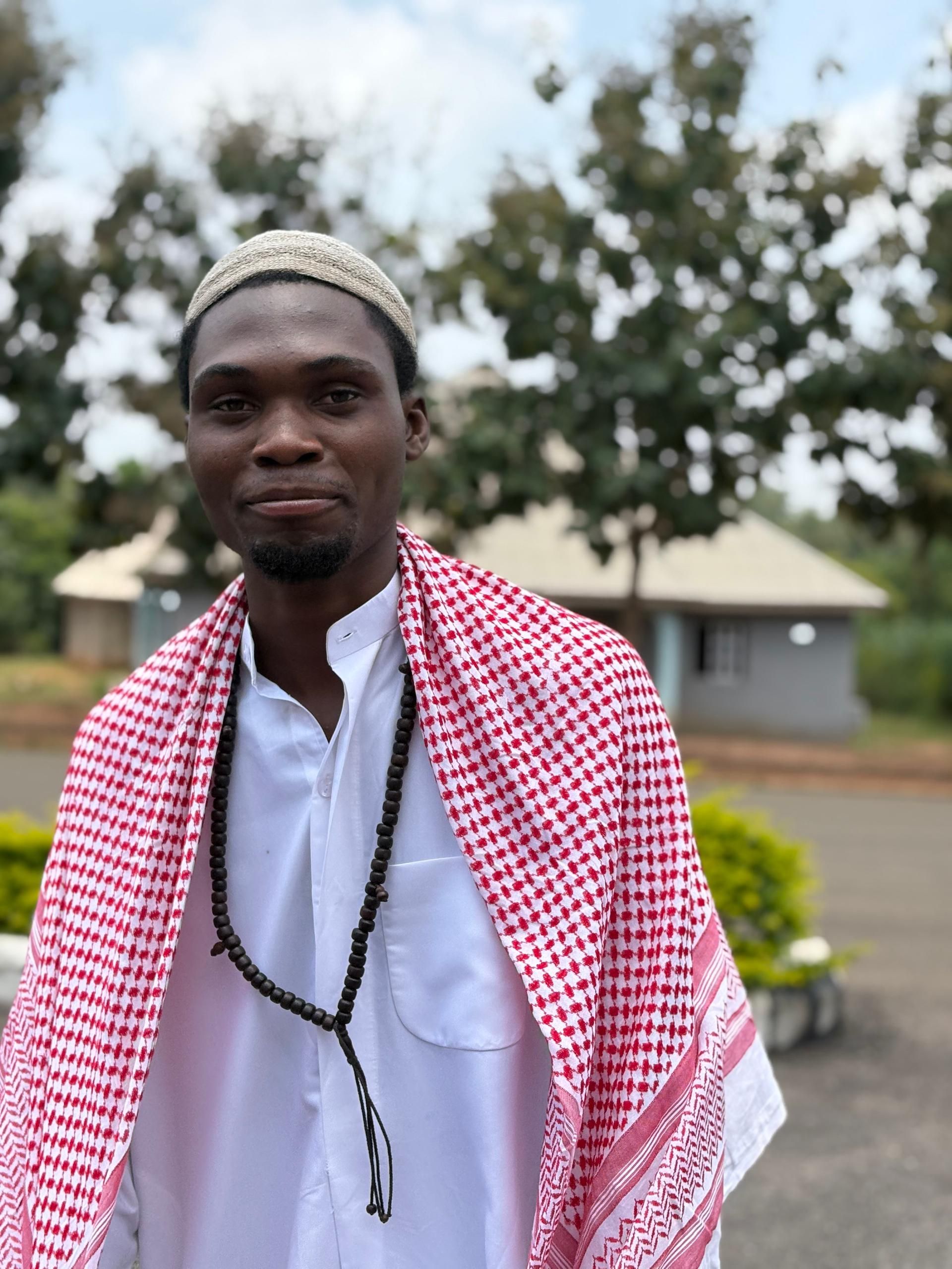 Man wearing traditional attire poses outdoors, exuding confidence and cultural pride.