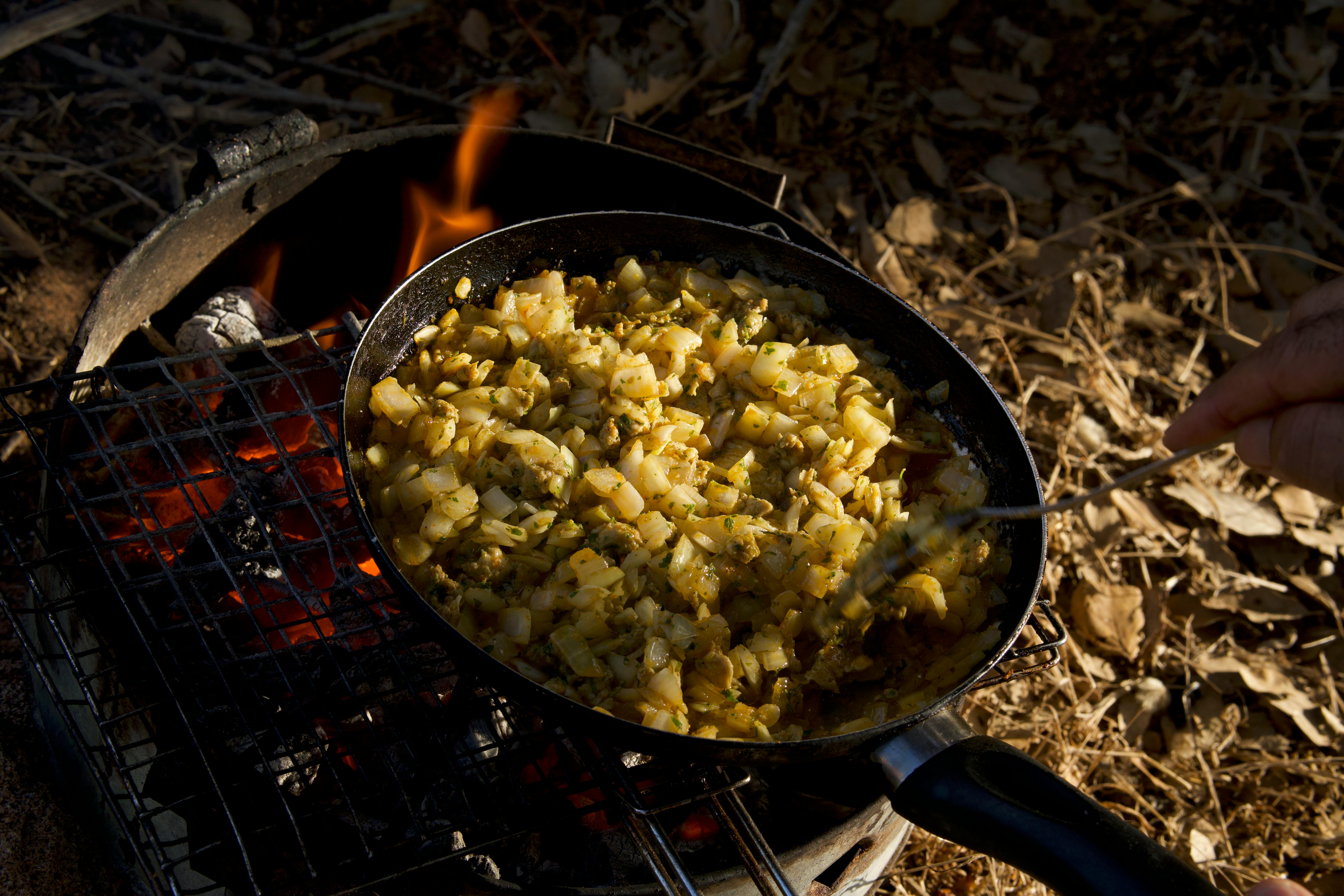 Delicious diced potatoes cooking on a fire grill outdoors. Perfect camping meal idea.