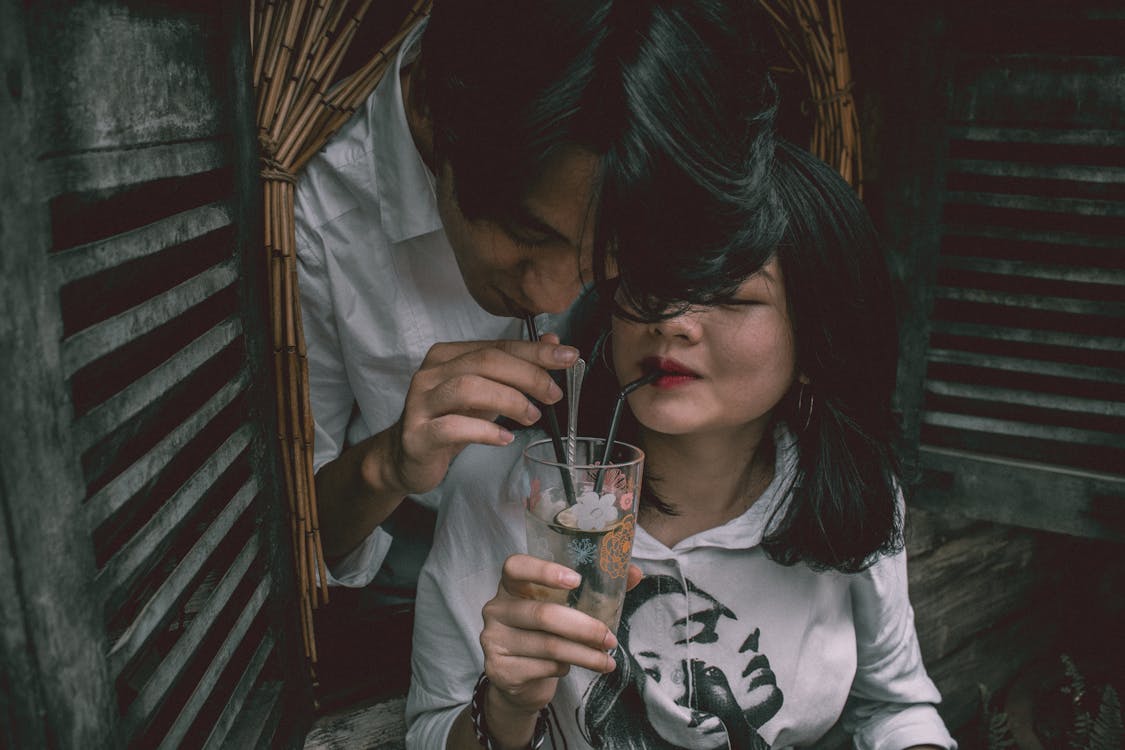 Free Man and Woman Sipping in Drinking Glass Stock Photo