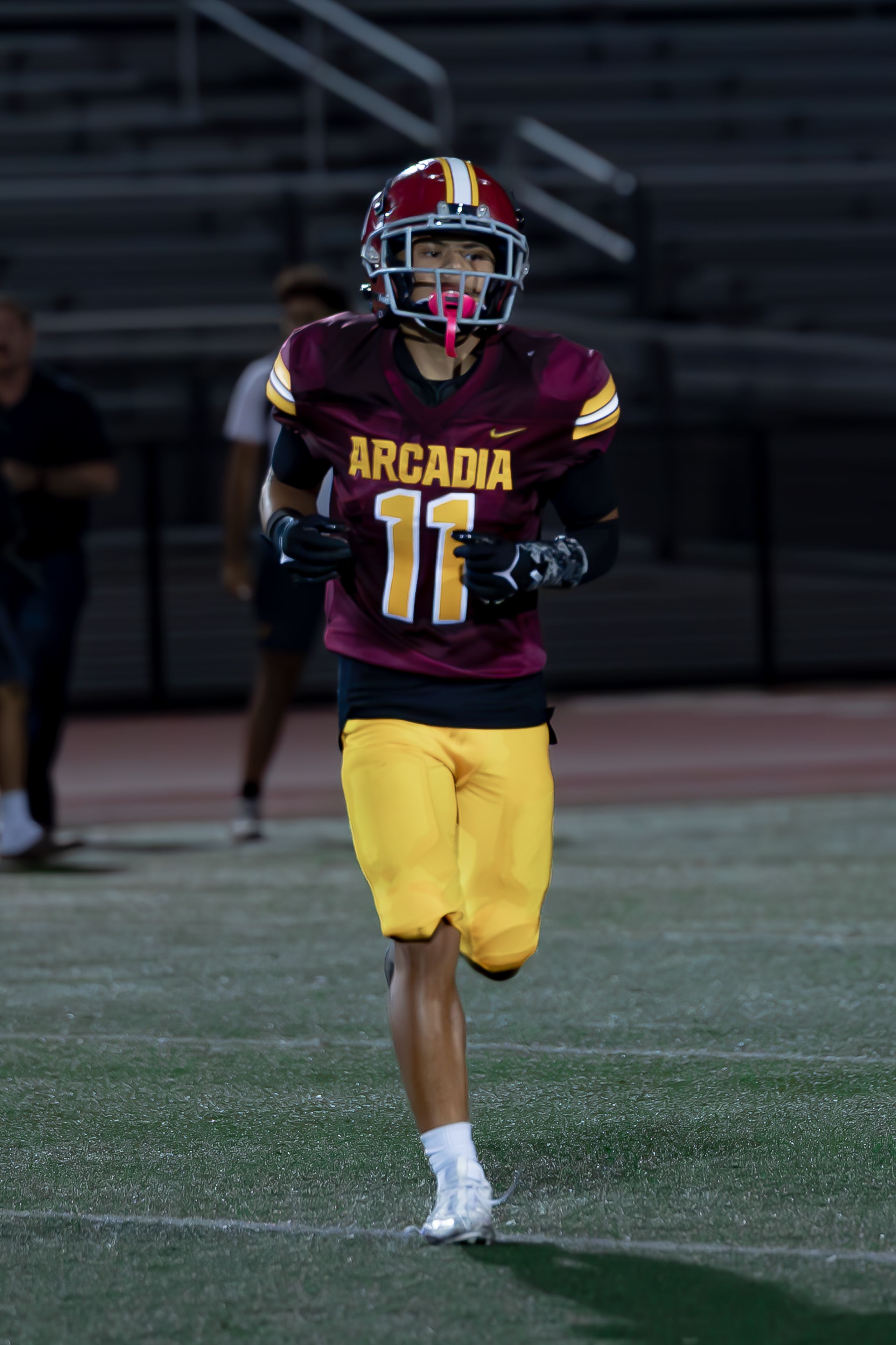 High school football player on the field during a nighttime game, showcasing athleticism and team spirit.