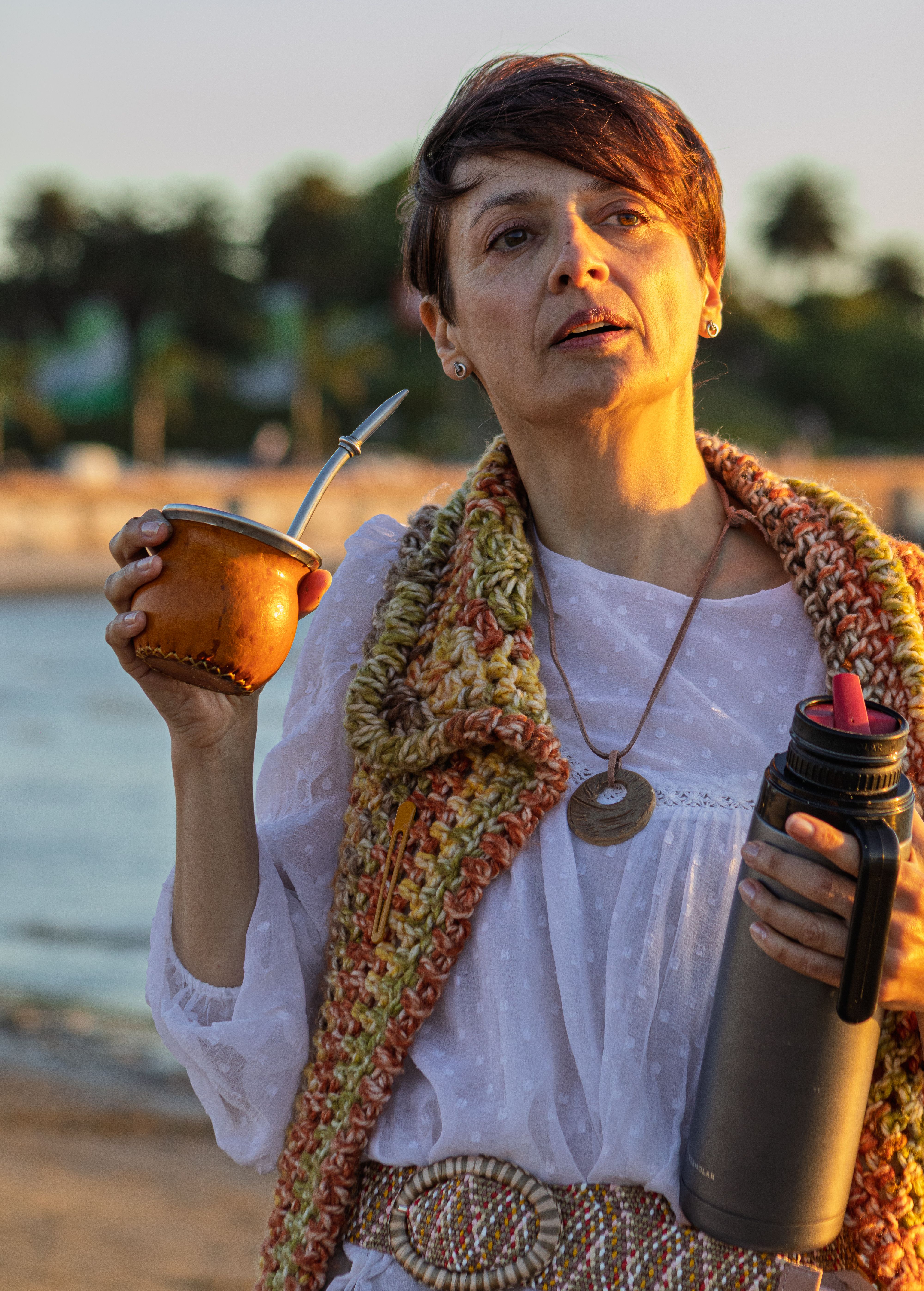 A woman on Montevideo beach enjoys drinking traditional Yerba Mate under the sunlight.