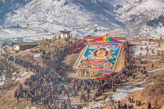 A colorful Buddhist festival celebrated on snowy hills, attracting a large crowd.