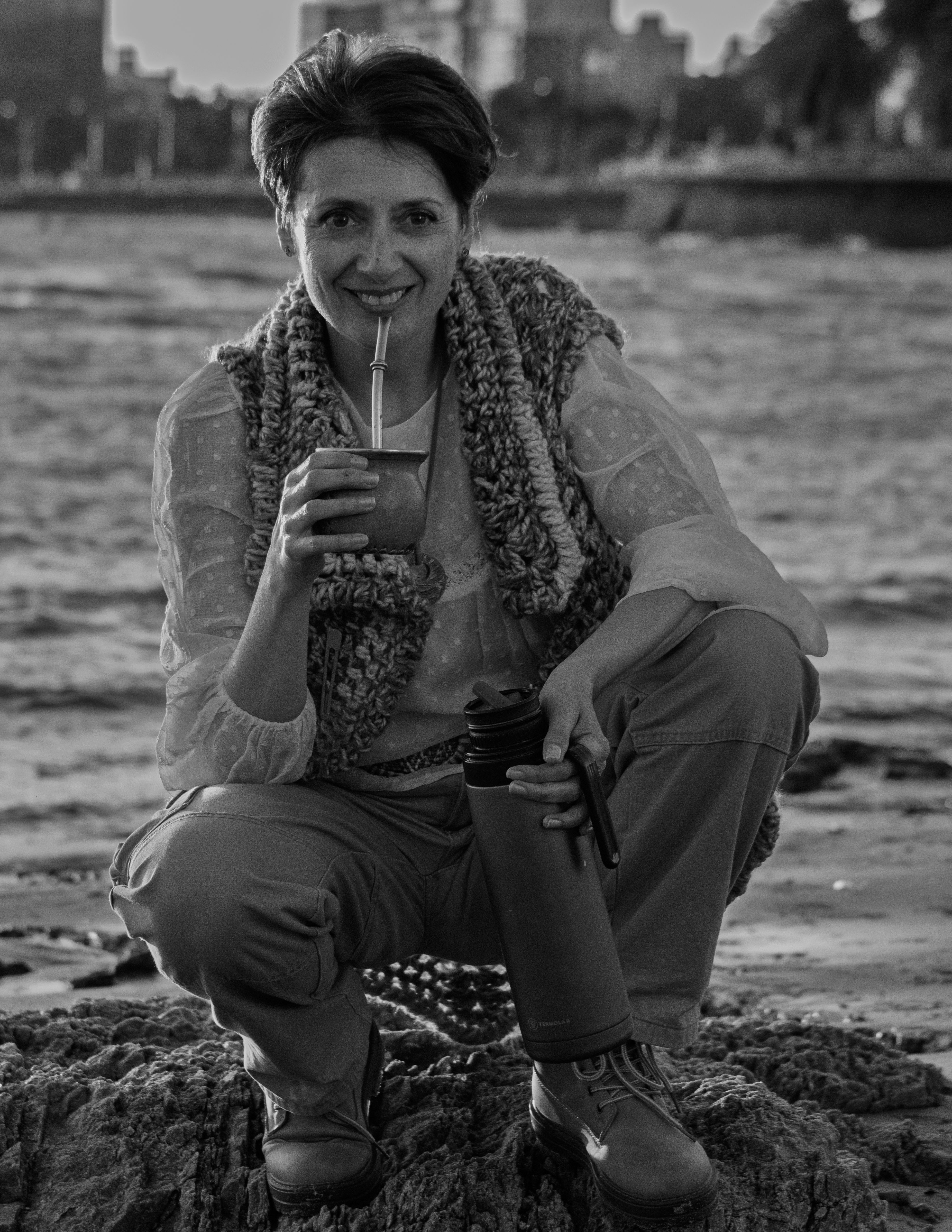 Candid shot of a woman savoring yerba mate on a beach in Montevideo, Uruguay during sunset.