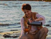 A woman relaxes on Montevideo’s shoreline enjoying a traditional yerba mate at sunset.