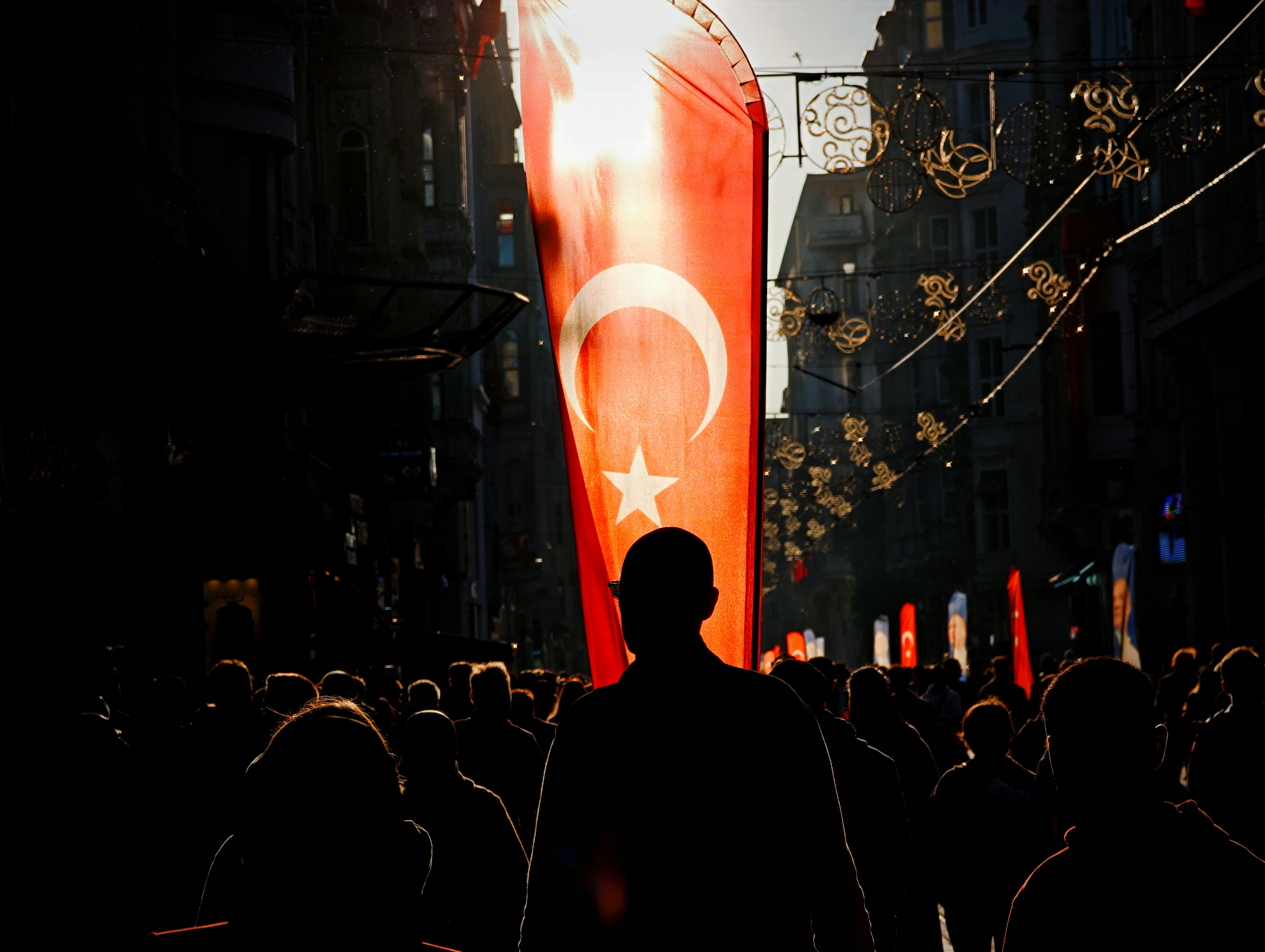 Gratis Silhouette di persone in via İstiklal a Istanbul con bandiera turca illuminata dalla luce del tramonto. Foto a disposizione