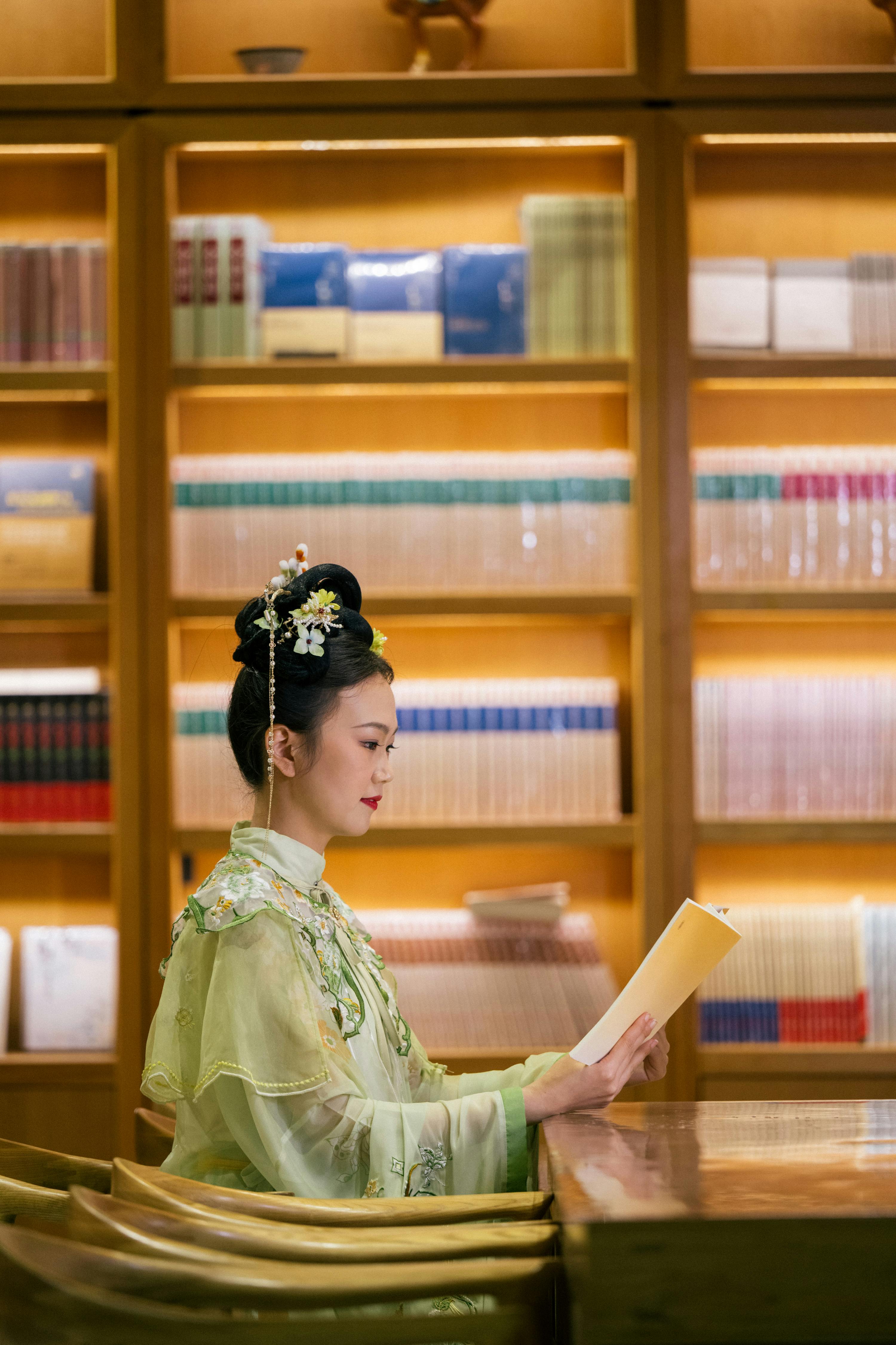 A woman in traditional clothing reads a paper in a warmly lit library, exuding elegance and cultural richness.
