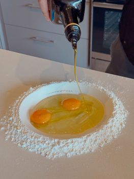 Making homemade pasta with eggs, flour, and olive oil preparation.