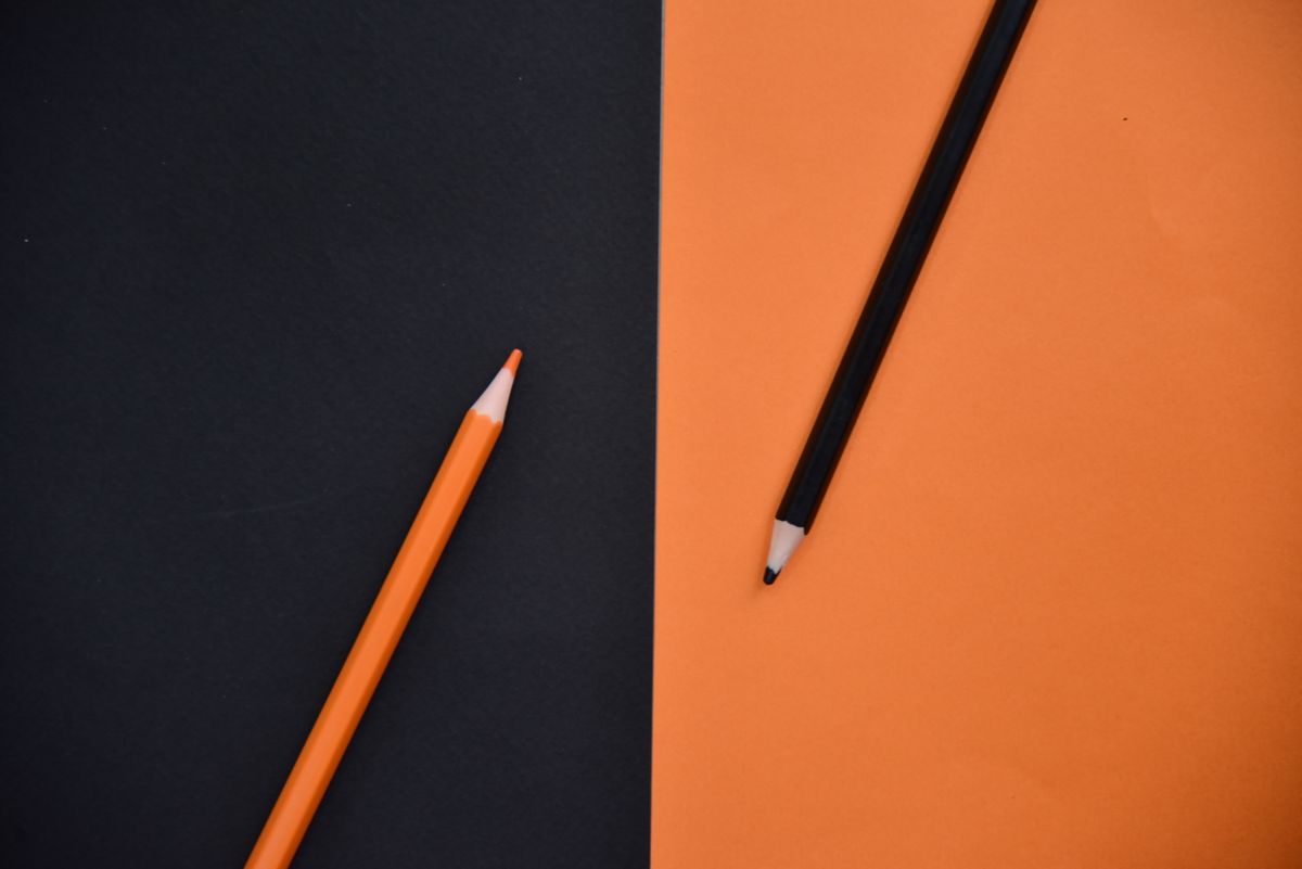 Orange and black pencils on coloured paper