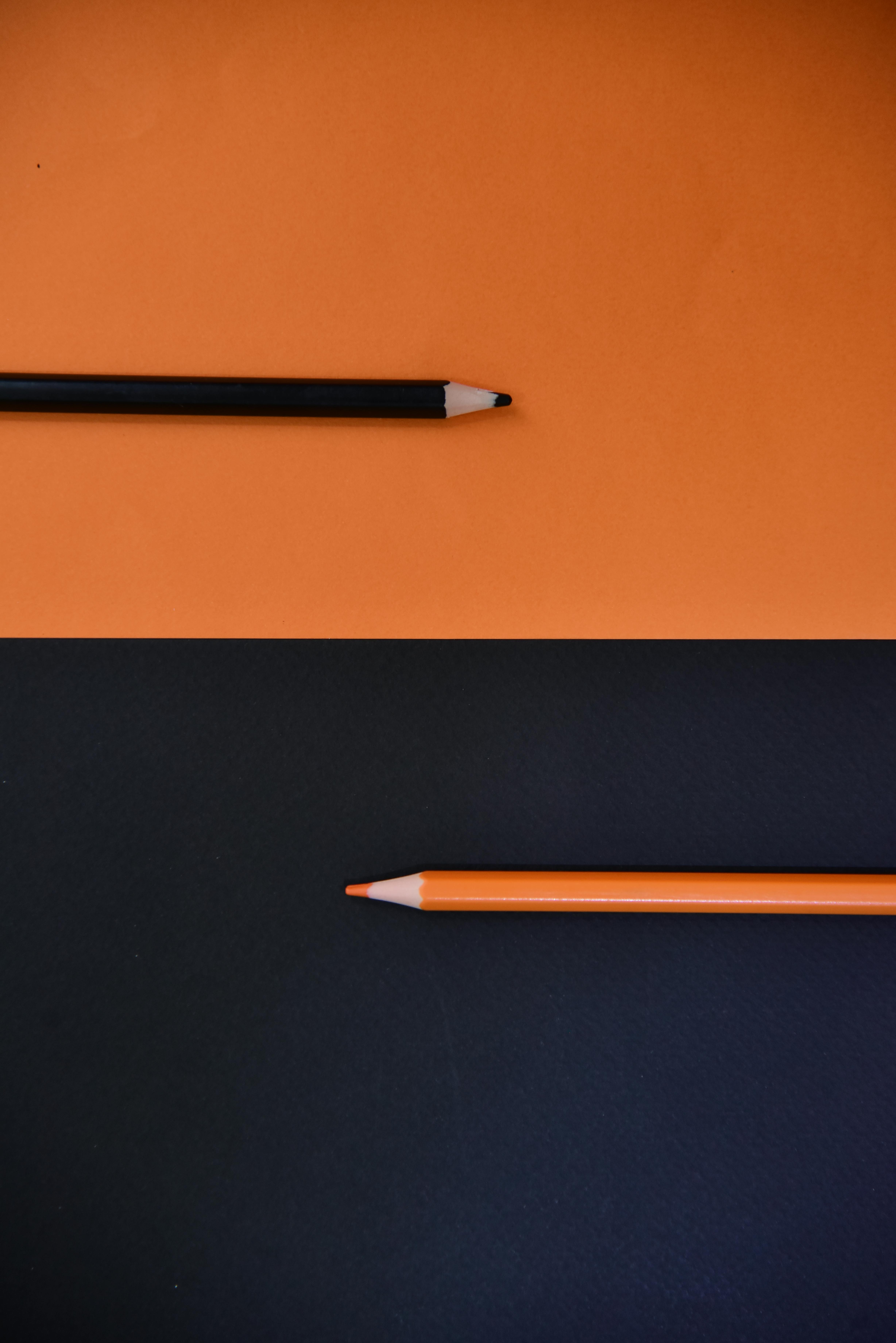 Gratuit Compoziție minimalistă cu creioane negre și portocalii pe fundaluri contrastante. Fotografie de stoc