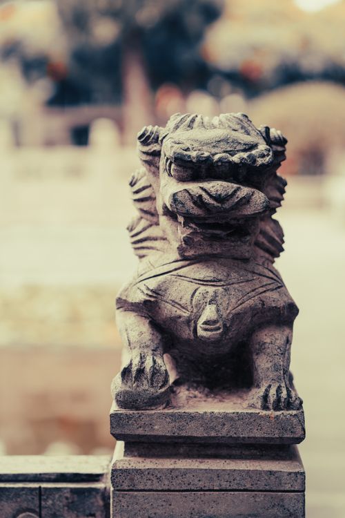 Free A stone guardian lion statue in a serene outdoor garden setting, exuding a calming and historical atmosphere. Stock Photo