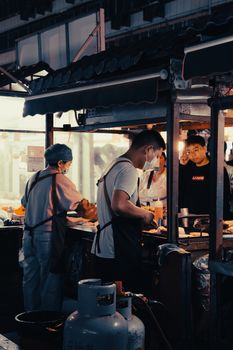 Candid view of chefs preparing street food at a vibrant night market.