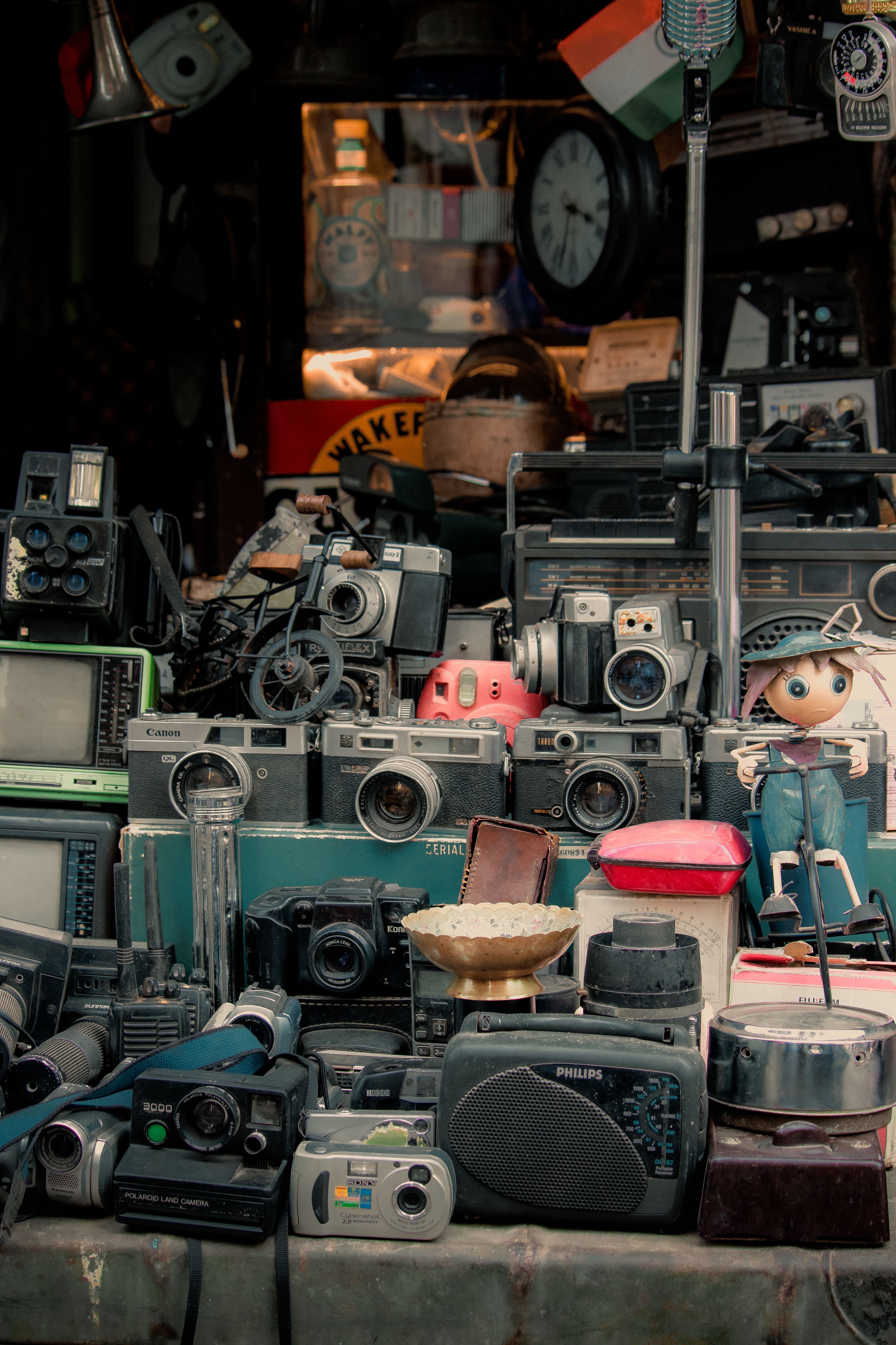 Collection of vintage cameras, radios, and electronics on display in an antique shop.