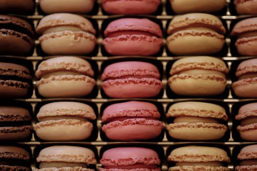 Close-up view of assorted colorful macarons perfectly arranged in rows on a tray.