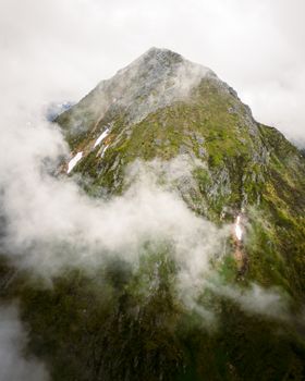 A dramatic aerial view of a foggy mountain peak in Austria's Styria region during summer.