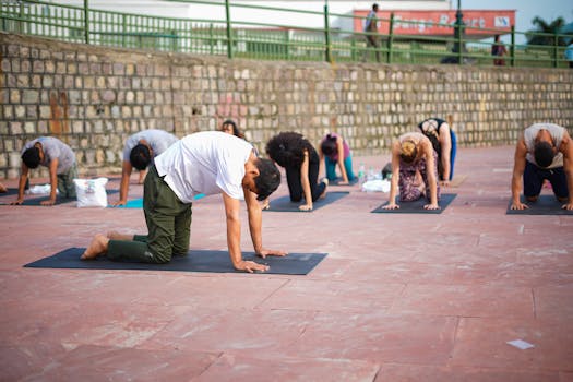A group of adults practicing yoga outdoors in Rishikesh, India, during the day.