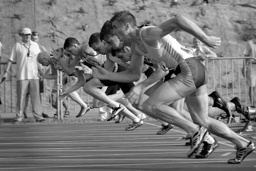 ورزشکاران در حال دویدن در مسیر و بیضوی در عکاسی در مقیاس خاکستری