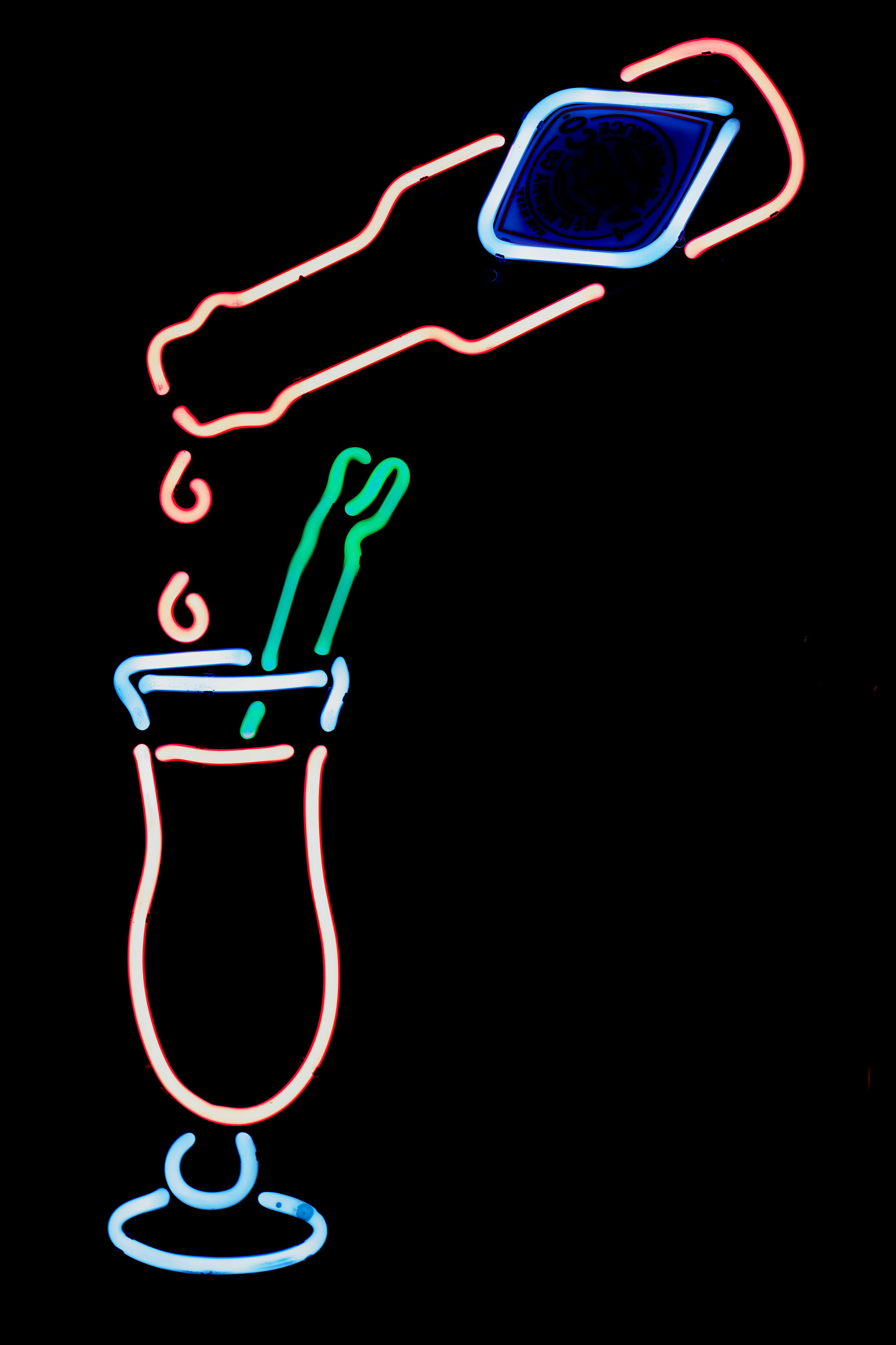 Gratis Insegna al neon colorata raffigurante un cocktail che viene versato, su uno sfondo scuro. Foto a disposizione