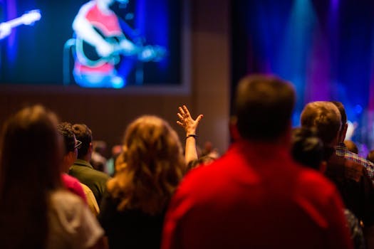 A lively audience enjoying a concert inside a venue, hand raised in excitement.