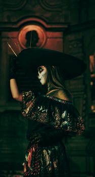 A striking portrait of a woman in a Catrina costume during a night celebration.
