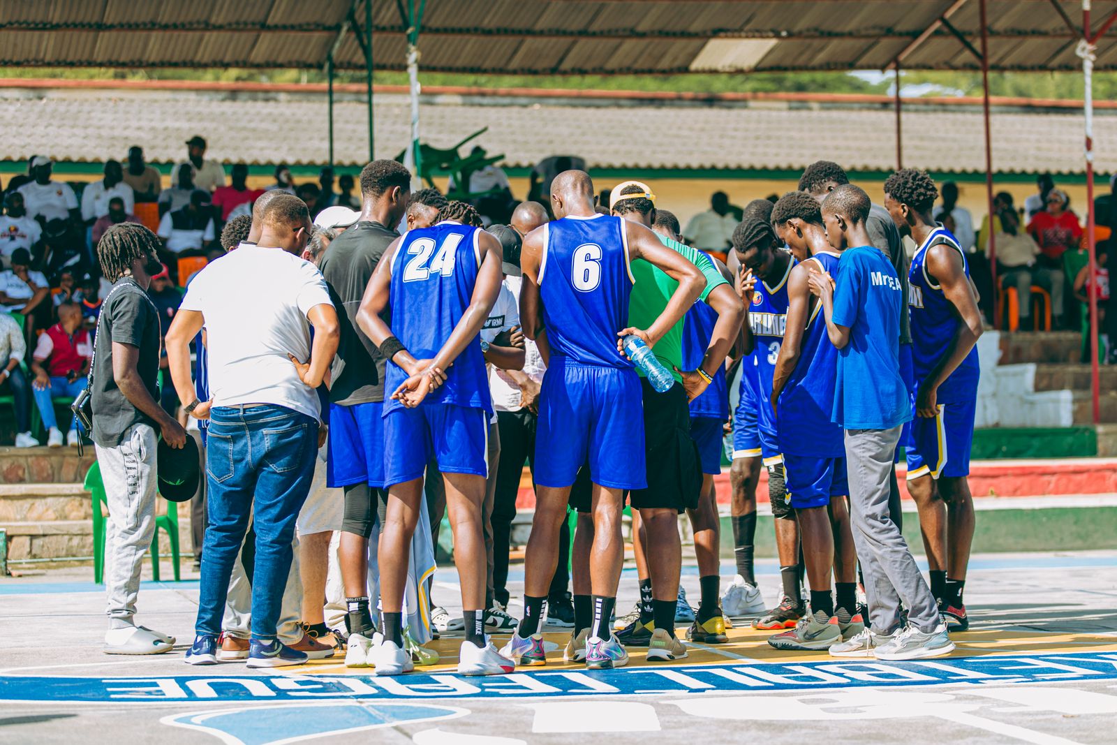 Basketball team in coordinated blue uniforms gathering courtside