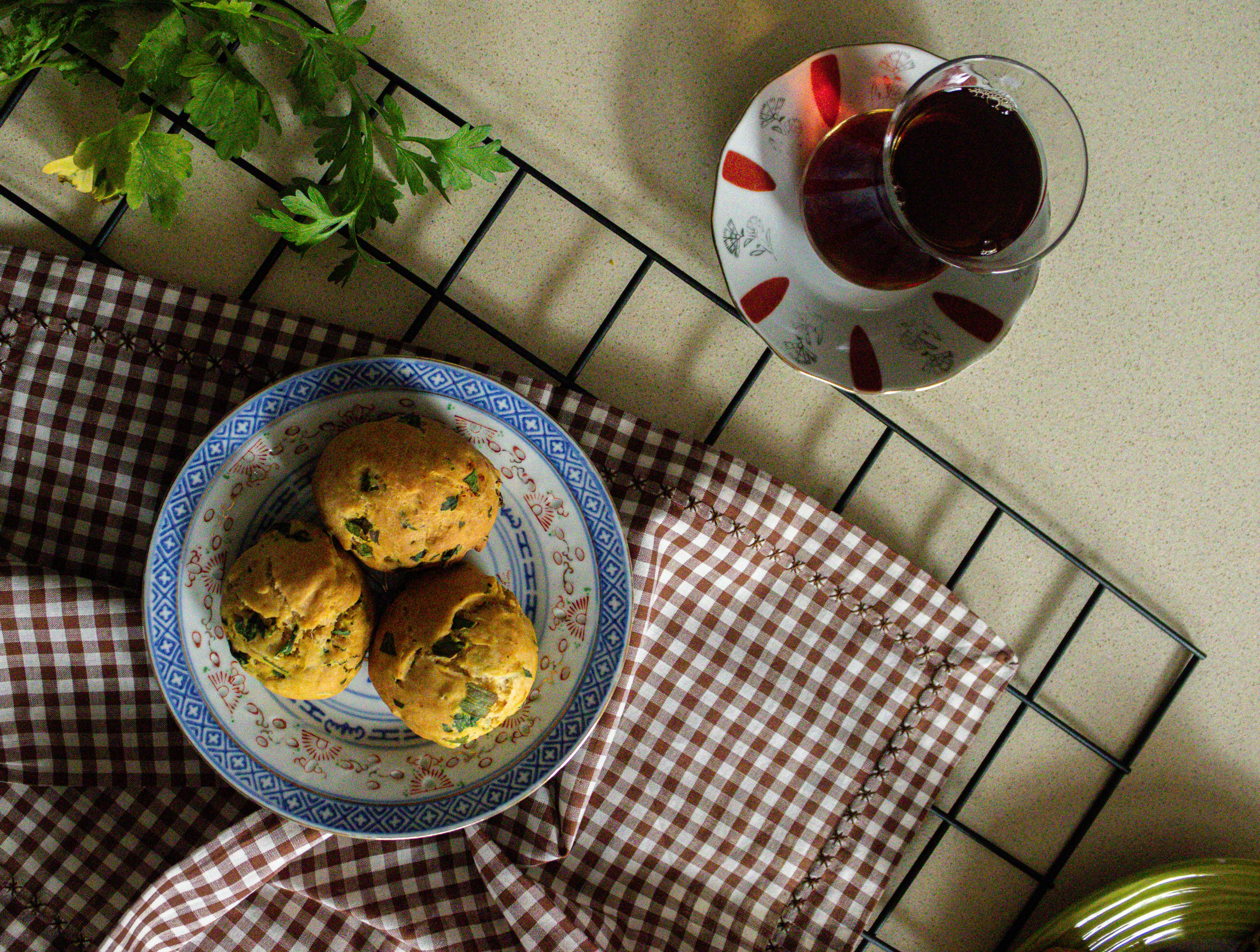 Top view of freshly baked herb muffins served with tea on a checkered cloth setting.