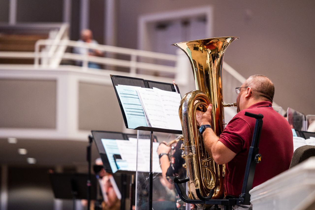 close up of a musician playing the tuba in a modern concert hall setti