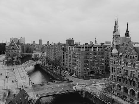 A black and white aerial view of a historic European city with canals and classic architecture.