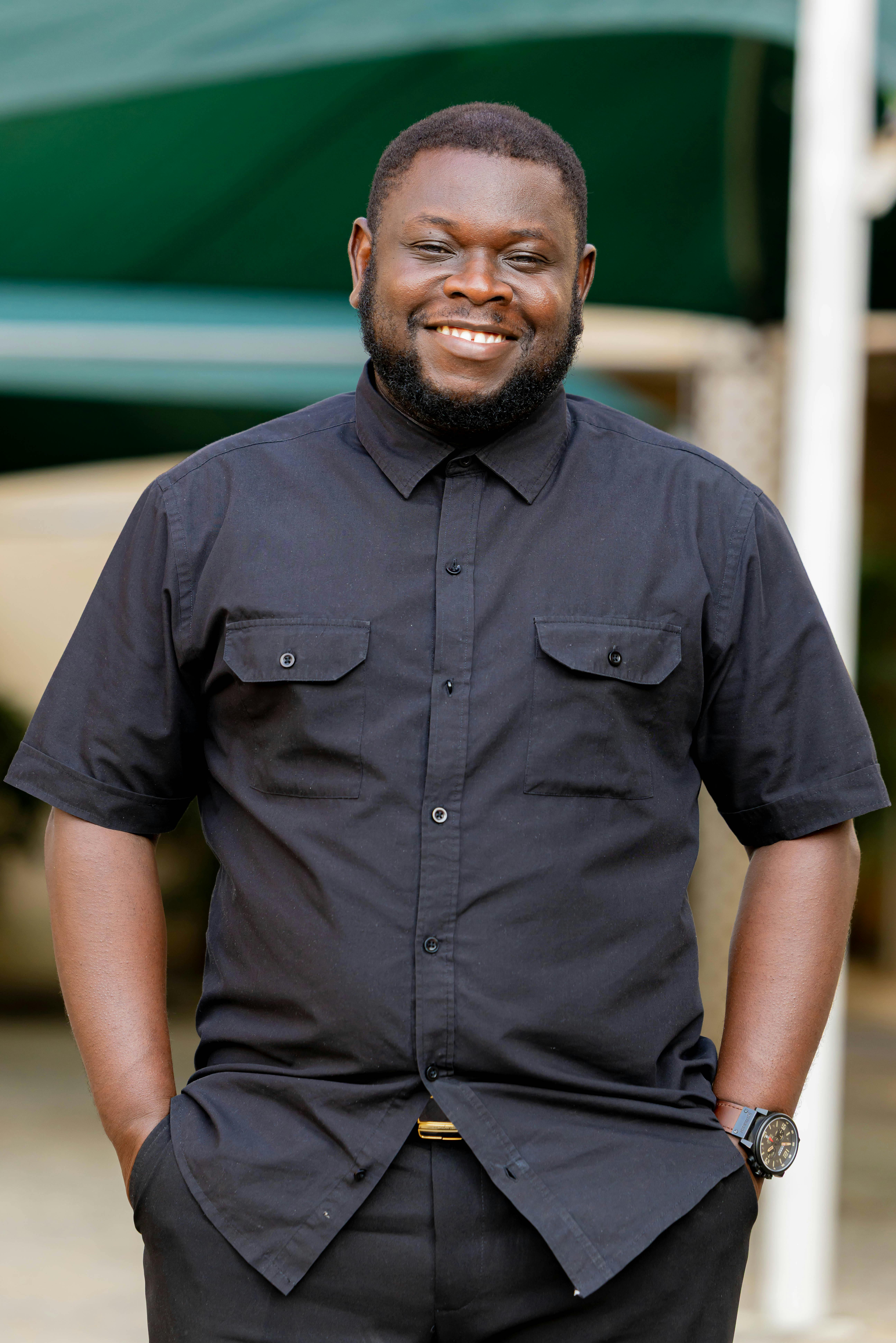 Happy man standing outdoors in a black shirt, exuding confidence and warmth.