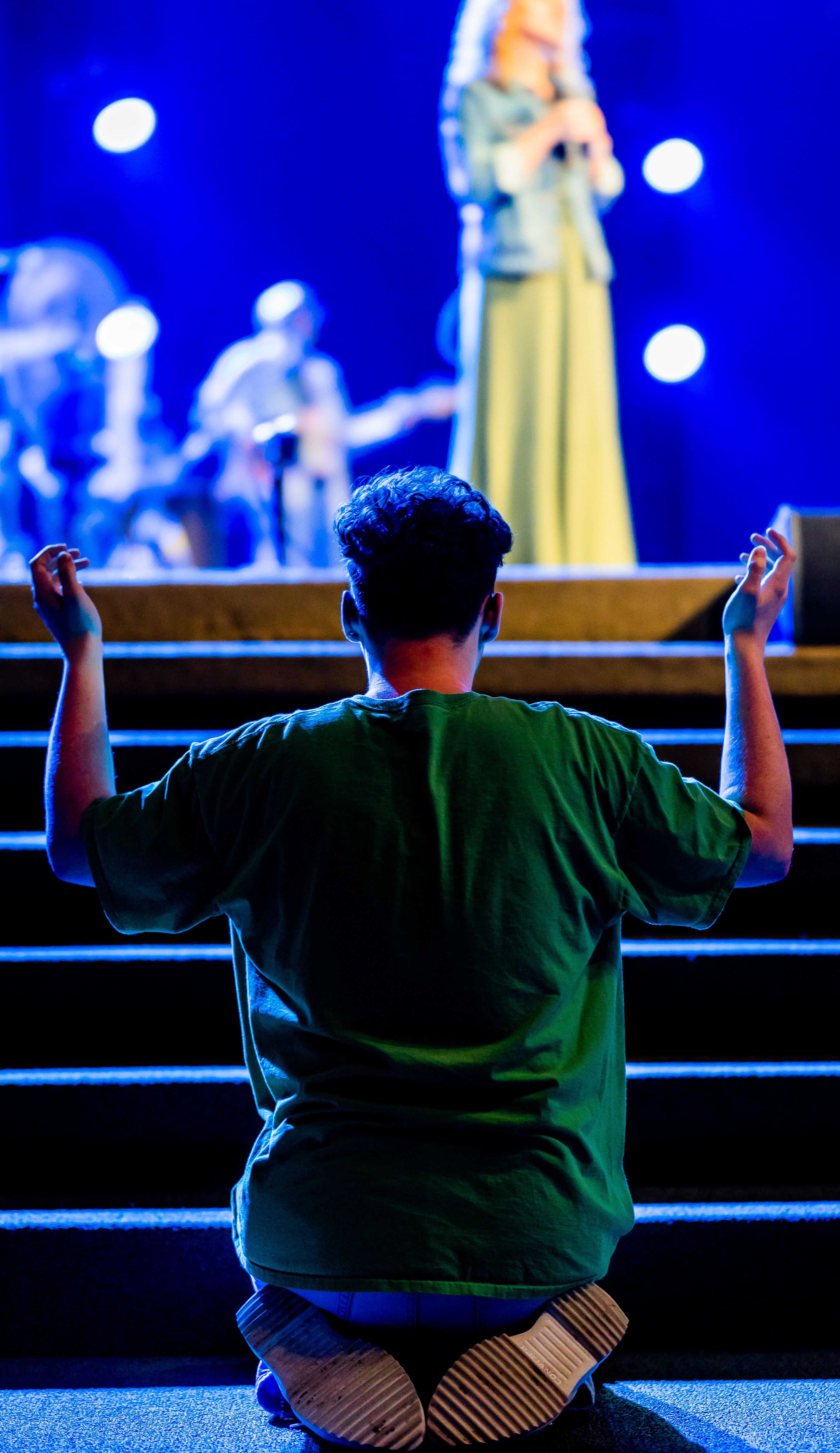 Person Kneeling in Prayer at Concert · Free Stock Photo
