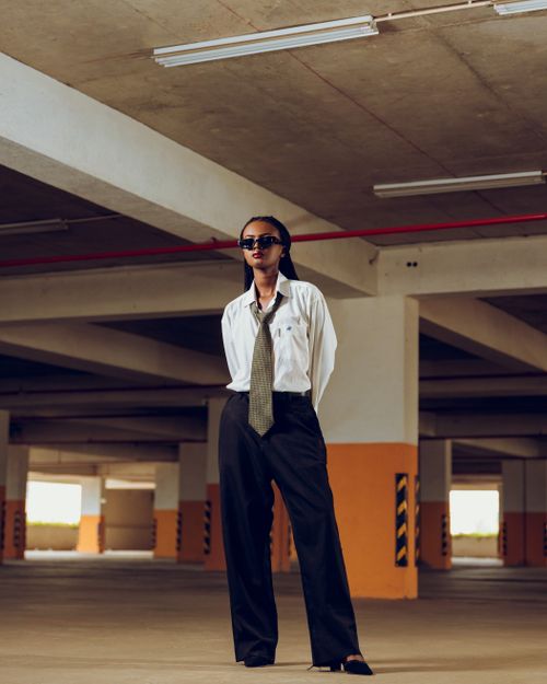 Free Elegant woman in sunglasses and formal wear stands confidently in a modern parking garage. Stock Photo