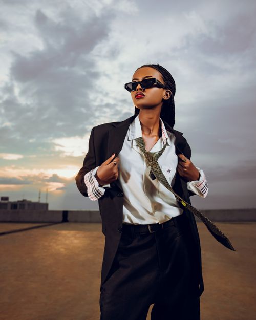 Free Stylish woman in sunglasses and suit poses against a dramatic sunset sky. Stock Photo
