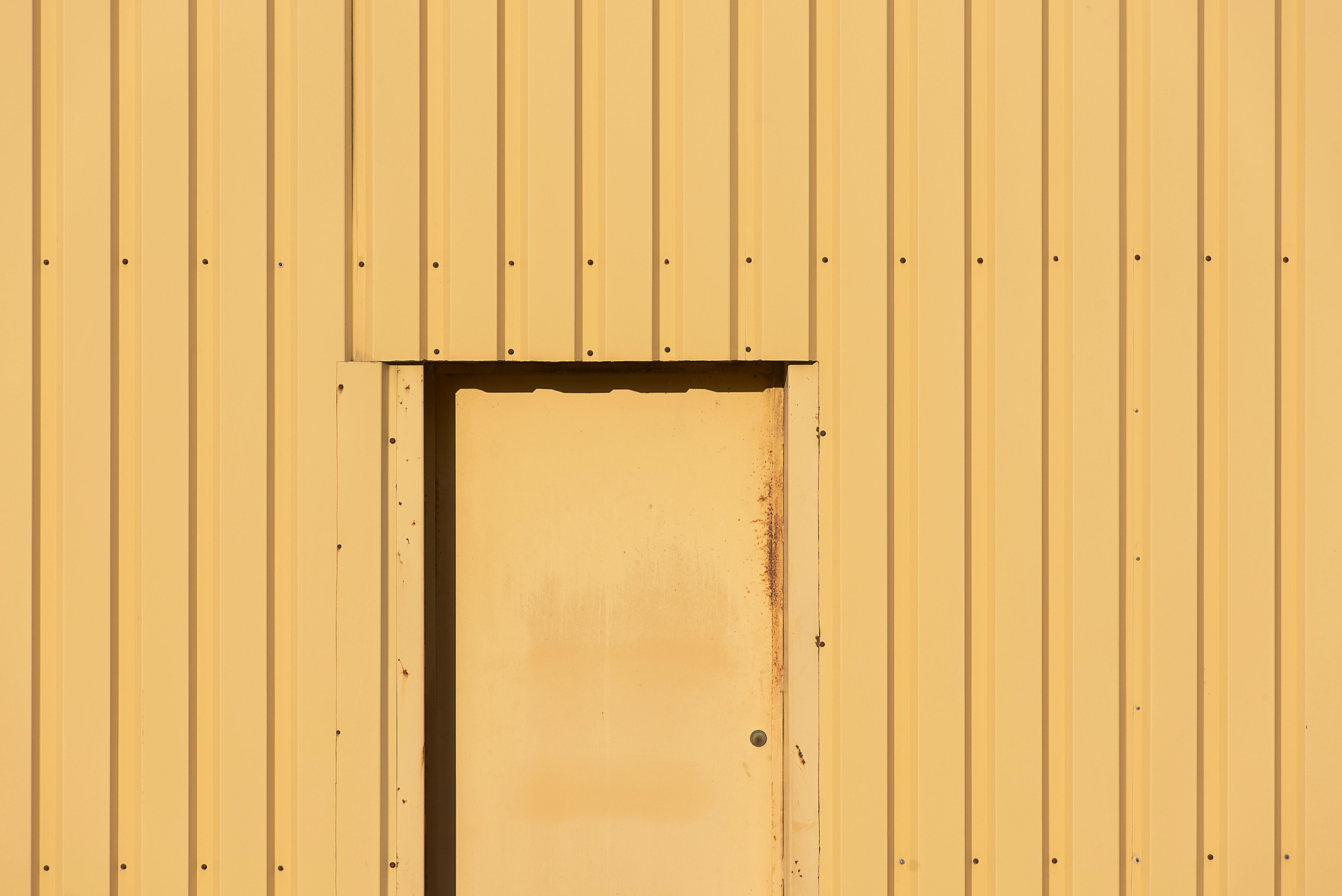 Gratuit O vedere minimalistă a unei uși galbene amplasată într-un perete industrial galben asortat. Fotografie de stoc