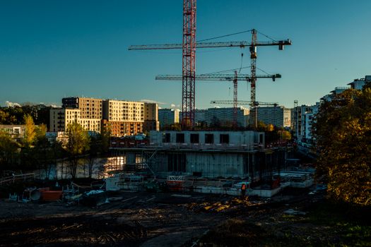 A vibrant urban construction scene with cranes and buildings under a twilight sky.