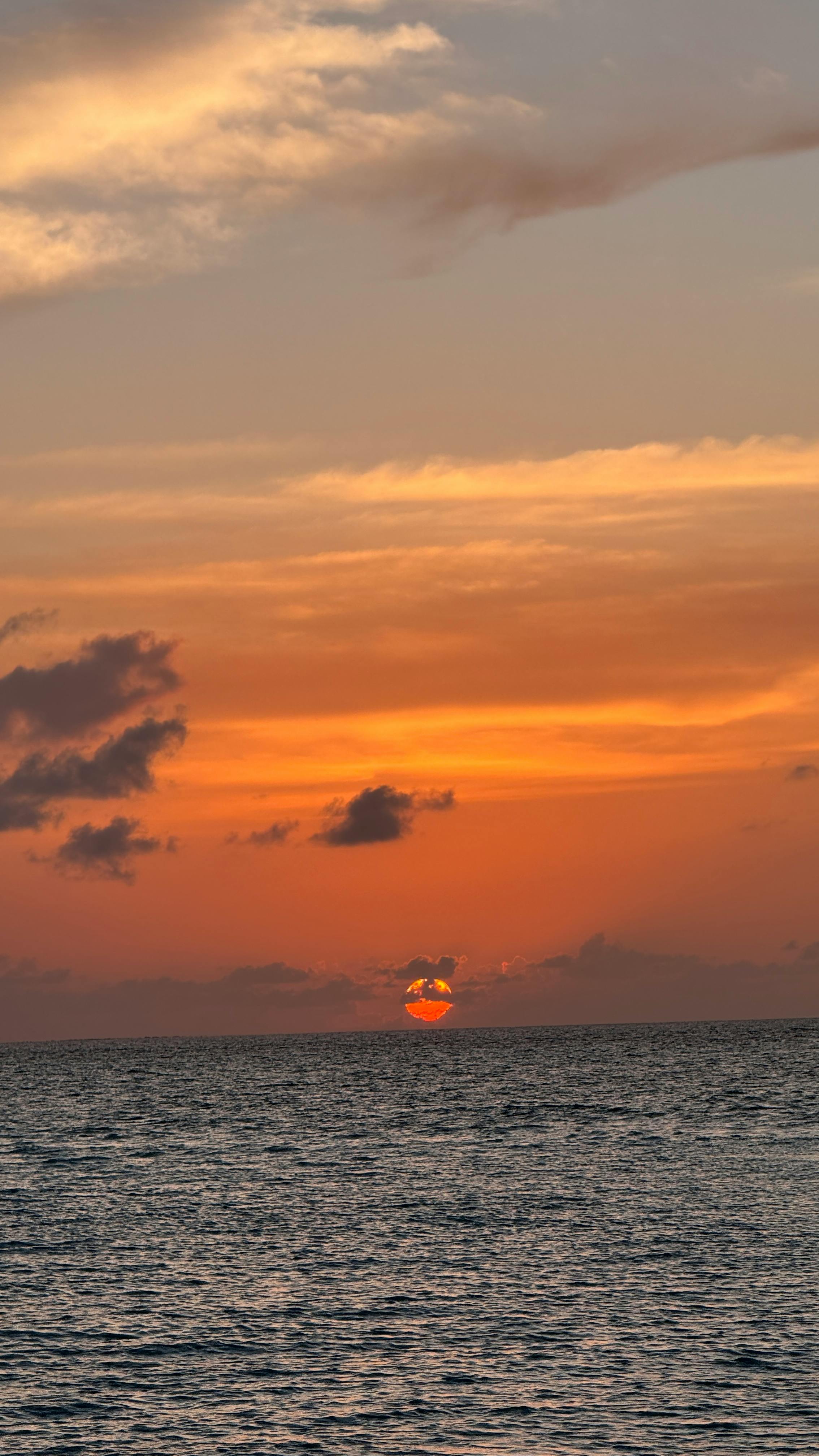 Beautiful sunset over the ocean in the Maldives with dramatic clouds and vibrant hues.